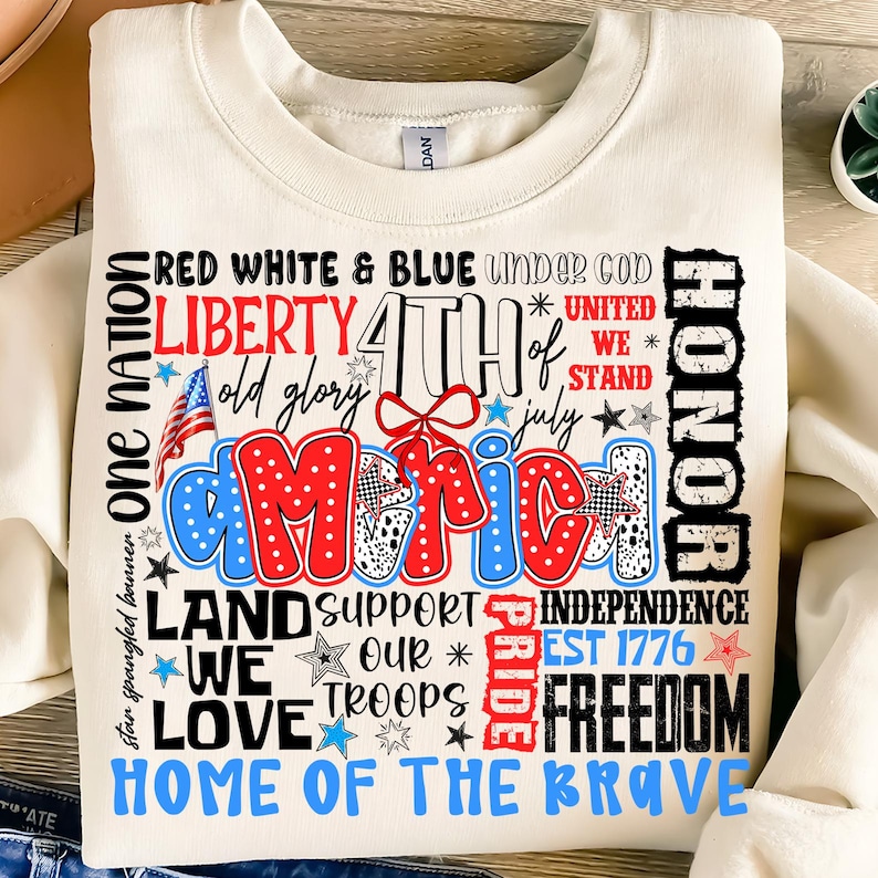 May include: A white sweatshirt with a red, white, and blue graphic design featuring the words "One Nation", "Liberty", "4th of July", "America", "Land Support", "We Love", "Our Troops", "Pride", "Independence", "Est 1776", "Freedom", and "Home of the Brave".