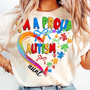 May include: A white t-shirt with the text "I'm a proud autism aunt" in a rainbow heart with puzzle pieces and bows.