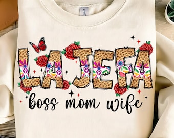 May include: A white sweatshirt with a colorful graphic design that says "La Jefa" with a butterfly and flowers. The text below the graphic says "boss mom wife".