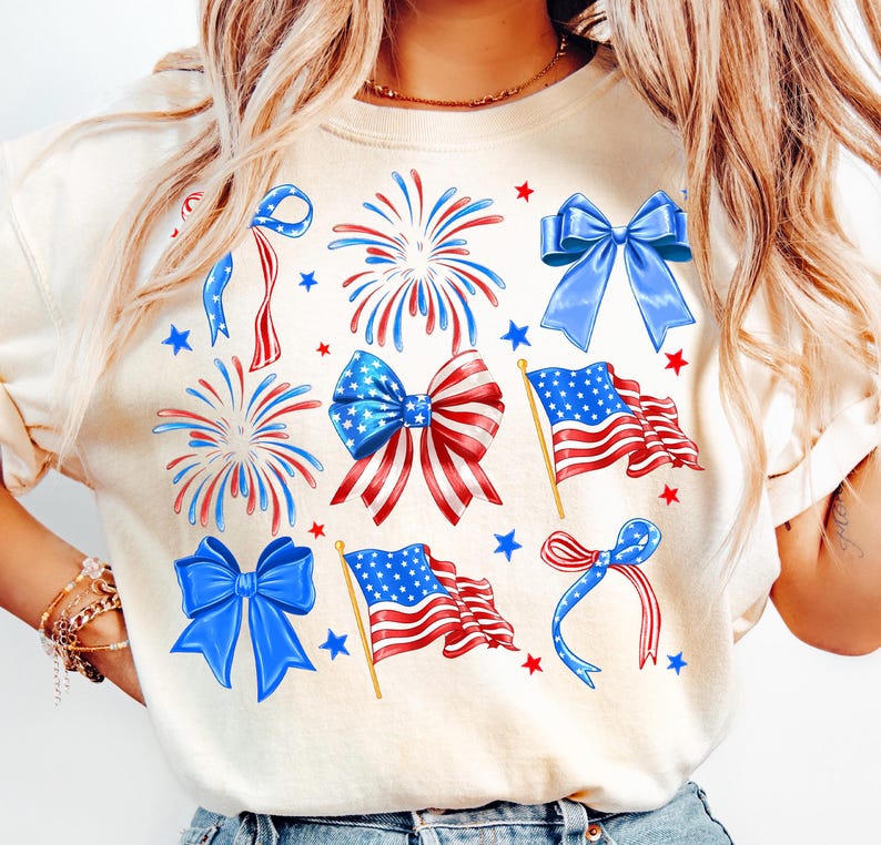 May include: A white t-shirt with a patriotic design featuring red, white, and blue stars, fireworks, bows, and American flags.