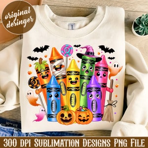 May include: Cream-colored sweatshirt featuring a colorful Halloween-themed crayon design. The design includes smiling crayons, pumpkins, ghosts, bats, and candy. The text "300 DPI SUBLIMATION DESIGNS PNG FILE" is at the bottom.