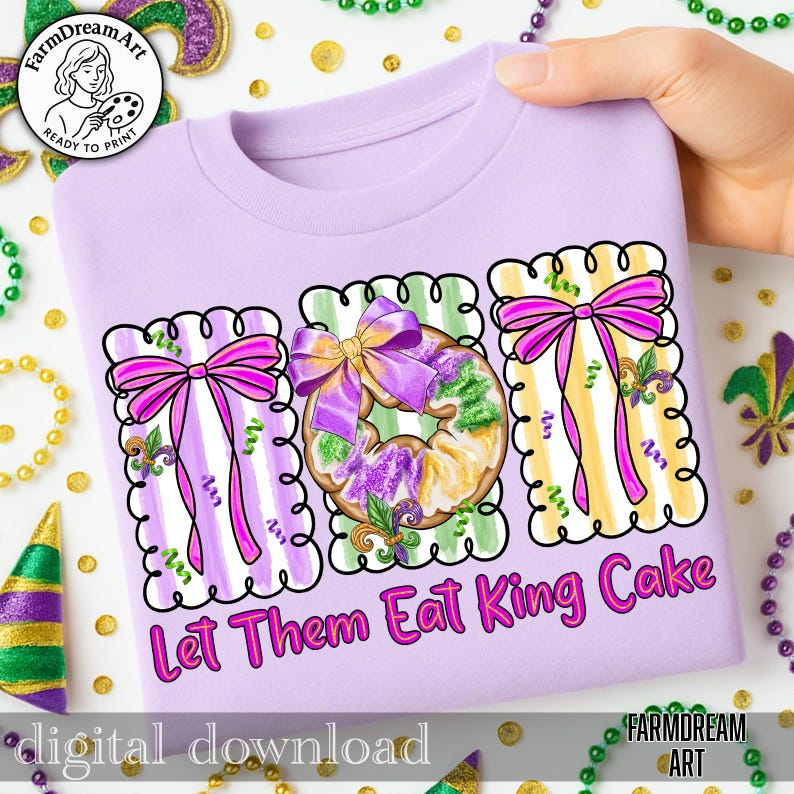 May include: A lilac t-shirt with a graphic design of three rectangular frames, each with a bow and a king cake design. The text "Let Them Eat King Cake" is below the frames. The shirt is decorated with Mardi Gras colours.