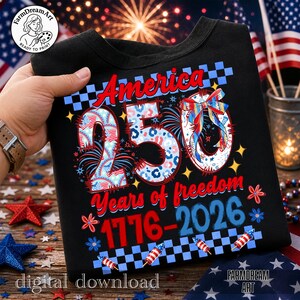 May include: Black t-shirt with the text "America 250 Years of freedom 1776-2026". The design includes the number 250 in a patriotic pattern, fireworks, and a bow. The shirt is held by a person.