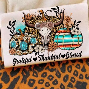 Puede incluir: Un dise&ntilde;o decorativo con calabazas, una calavera y detalles florales. Las calabazas tienen varios patrones, incluyendo estampado de leopardo y adornos turquesa. El texto dice "Grateful Thankful Blessed".