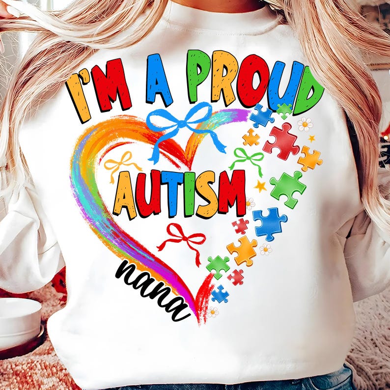 May include: White sweatshirt with a rainbow heart design and the text "I'm a proud autism nana". The heart is surrounded by puzzle pieces in various colors.