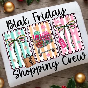 May include: White towel with the words "Blak Friday Shopping Crew" in black script. The design features three striped panels with bows, snowflakes, a shopping cart with gifts, a shopping bag, and a sale tag.