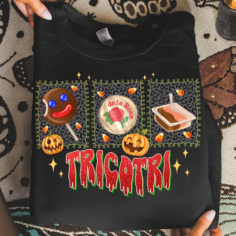 K&ouml;nnte beinhalten: Schwarzes Sweatshirt mit einem Halloween-Motiv. Das Design umfasst einen Lebkuchenmann-Lutscher, eine "de la Rosa" S&uuml;&szlig;igkeit und ein kleines Dessert, alles innerhalb eines Leopardenmuster-Rands. Das Wort "TRICOTRI" ist in Rot und Gr&uuml;n geschrieben.