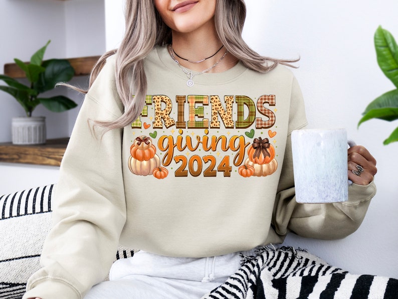 May include: A beige sweatshirt with the text "FRIENDS giving 2024" in a patchwork style with autumnal colours and pumpkins.