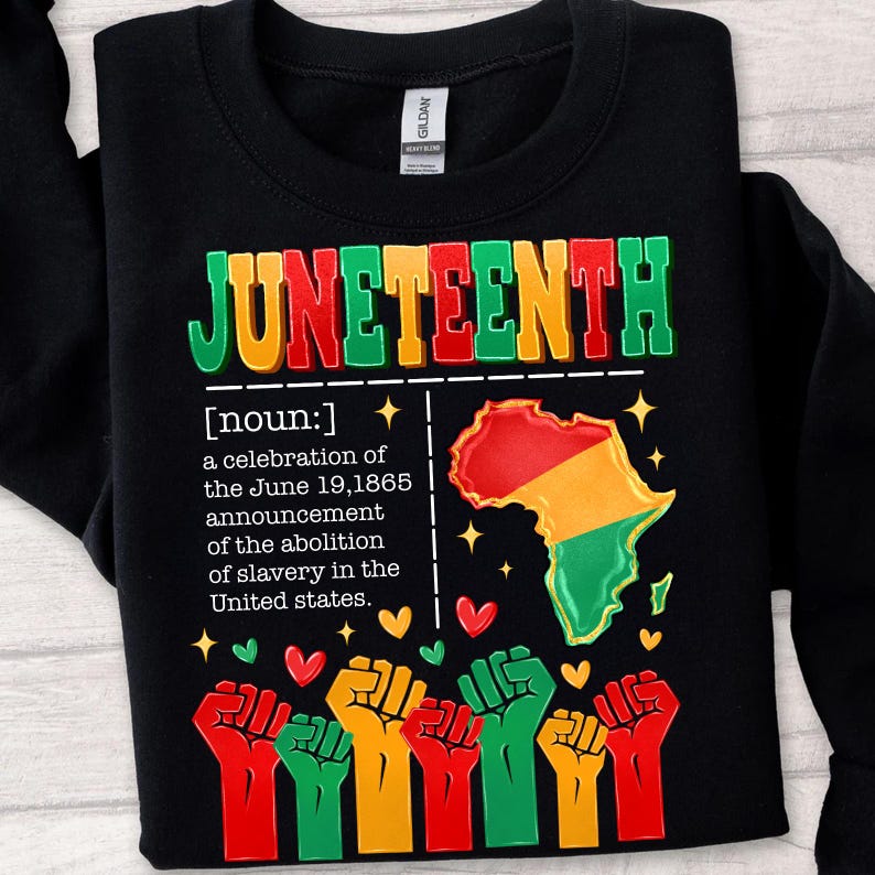 May include: Black sweatshirt with the word "JUNETEENTH" in green, red, and yellow block letters. The design includes a map of Africa in red, yellow, and green, along with text describing the holiday and raised fists.