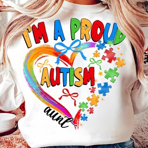 May include: White sweatshirt with a rainbow heart and the text "I'm a proud autism aunt". The heart is surrounded by puzzle pieces and bows.