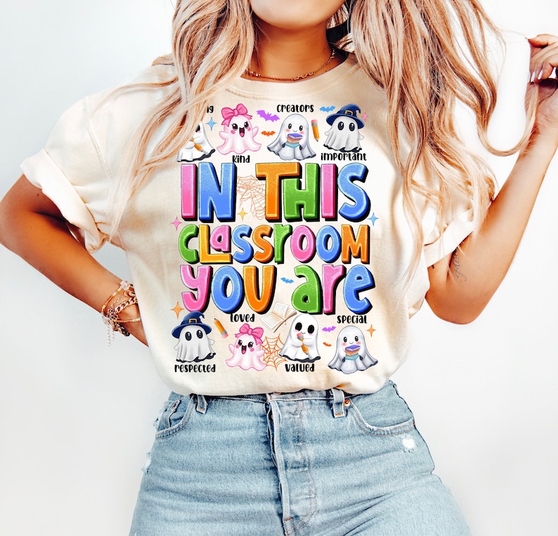 May include: A white t-shirt with a colorful graphic that says "In this classroom you are" surrounded by cute ghost illustrations. Each ghost has a different word on it, such as "creators", "kind", "important", "loved", "respected", "valued", and "special".