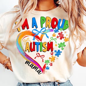 May include: A white t-shirt with a rainbow heart design and the text "I'm a proud autism mama". The heart is filled with puzzle pieces and bows.