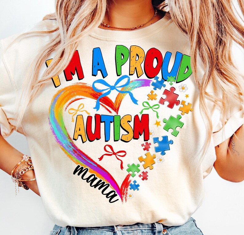 May include: A white t-shirt with a rainbow heart design and the text "I'm a proud autism mama". The heart is filled with puzzle pieces and bows.