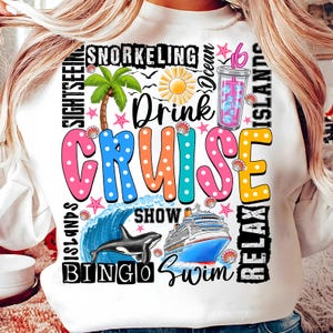 May include: White sweatshirt with a colorful graphic design that says "Drink Cruise" with images of a cruise ship, a dolphin, a palm tree, a drink, and other cruise-related icons.