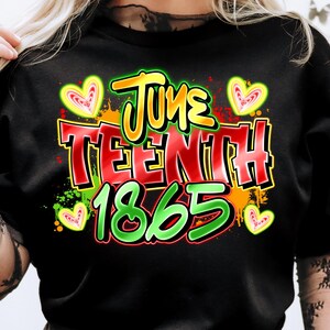 May include: Black t-shirt with a colorful graphic design. The design features the words "June TEENTH 1865" in bold, outlined letters, with heart shapes and paint splatter accents. The text is in green, yellow, and red.