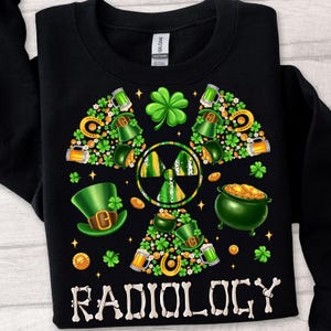 May include: Black sweatshirt with a green shamrock and gold coins design. The design is a stylized radiation symbol with the word "RADIOLOGY" in white letters below it.