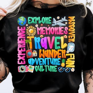 May include: Black t-shirt with colorful text that says "Experience Explore Memories Travel Wander Adventure Culture Discover Fun". The text is surrounded by images of a globe, airplane, sun, palm tree, camera, sunglasses, pineapple, and flowers.
