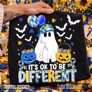 May include: A black t-shirt featuring a white ghost wearing a blue and yellow puzzle-patterned baseball cap, holding two balloons and two jack-o'-lantern buckets filled with puzzle pieces, surrounded by bats and the text IT'S OK TO BE DIFFERENT.