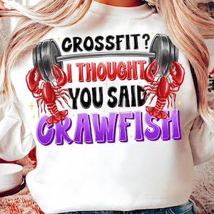 Può includere: Felpa bianca con una grafica viola e nera che dice "Crossfit? Pensavo avessi detto gambero" con un gambero rosso su ogni lato della barra.