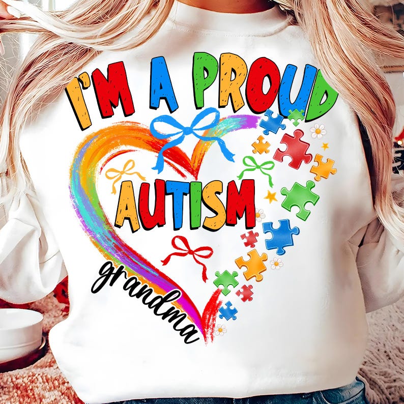 May include: White sweatshirt with a rainbow heart and the words "I'm a proud autism grandma". The heart is surrounded by puzzle pieces in various colors.