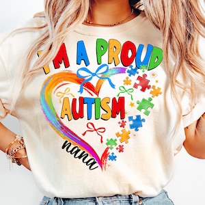 May include: A white t-shirt with a rainbow heart design and the text "I'm a proud autism nana". The heart is surrounded by puzzle pieces and bows.