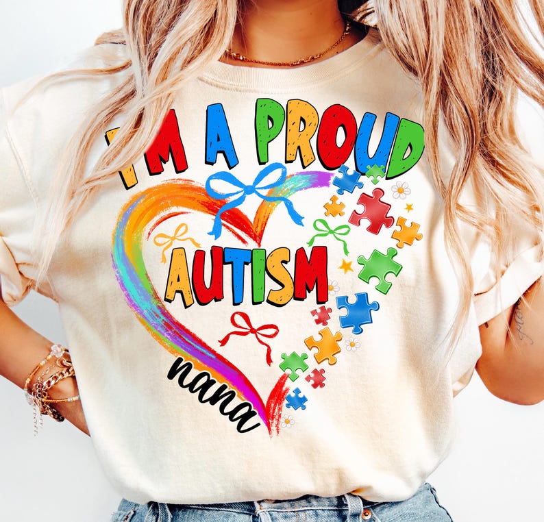May include: A white t-shirt with a rainbow heart design and the text "I'm a proud autism nana". The heart is surrounded by puzzle pieces and bows.