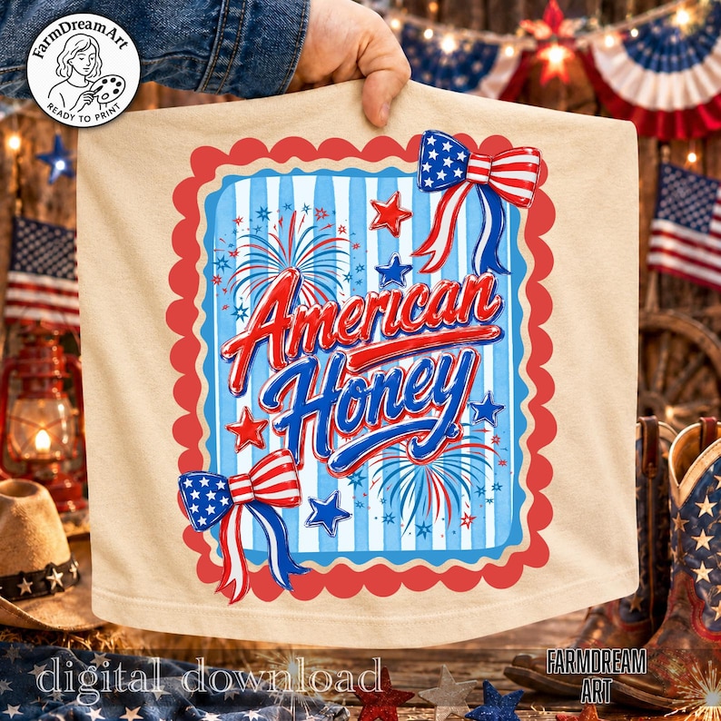 May include: A beige t-shirt featuring a patriotic design with the words "American Honey" in red and blue script. The design includes fireworks, stars, and bow accents in red, white, and blue. The shirt is held up by a person.