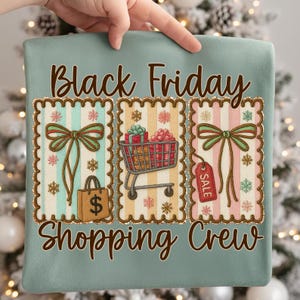 May include: A light teal pillow with the words "Black Friday Shopping Crew" in brown script. The design features three rectangular postage stamp-like images with bows, a shopping cart, a shopping bag, and a sale tag.