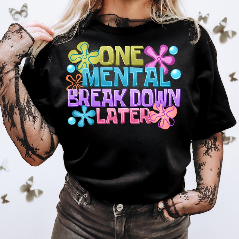 May include: Black t-shirt with a colorful graphic that says "One Mental Break Down Later" with flower-like designs.