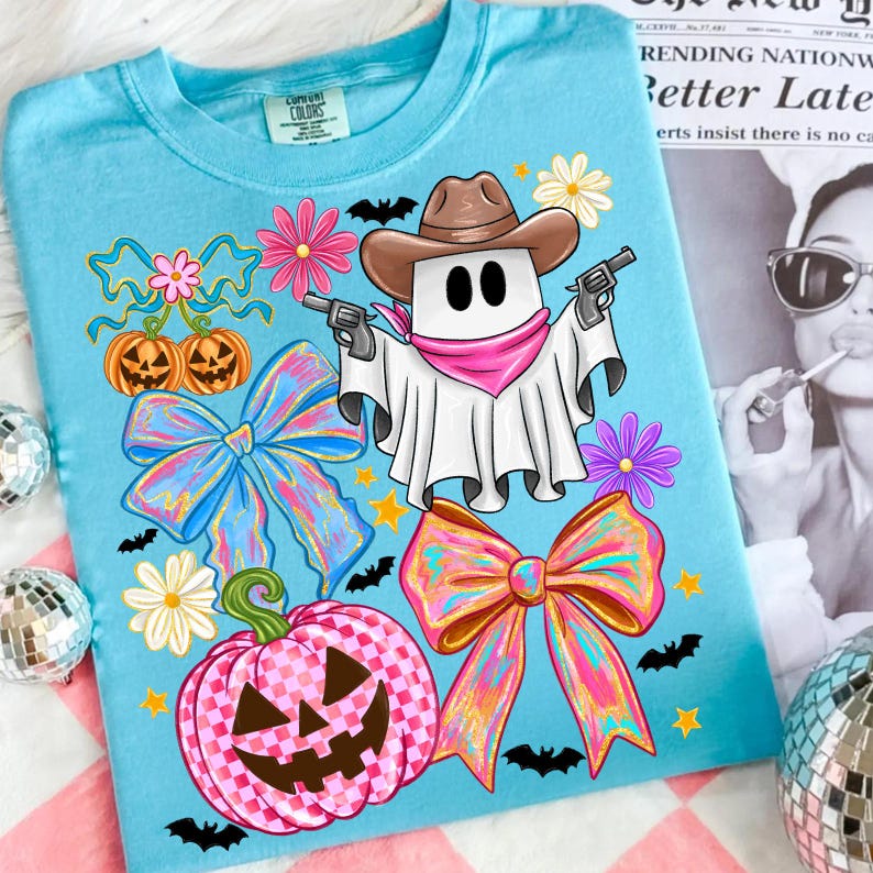 May include: A light blue t-shirt with a cartoon ghost in a cowboy hat holding guns. The design includes pumpkins, bows, flowers, bats, and stars, all in a Halloween theme.