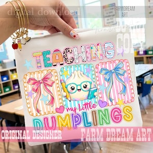 May include: A white t-shirt featuring a colorful graphic with the text TEACHING my little DUMPLINGS. The design includes a cartoon dumpling wearing teal glasses, holding a pencil and book, flanked by a pink bow and a blue bow in frames.