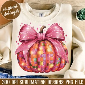 May include: Cream-colored sweatshirt featuring a vibrant, mosaic-style pumpkin design with a large pink bow. The pumpkin is composed of colorful squares, and the design includes sparkling accents. Text at the bottom reads "300 DPI SUBLIMATION DESIGNS PNG FILE."