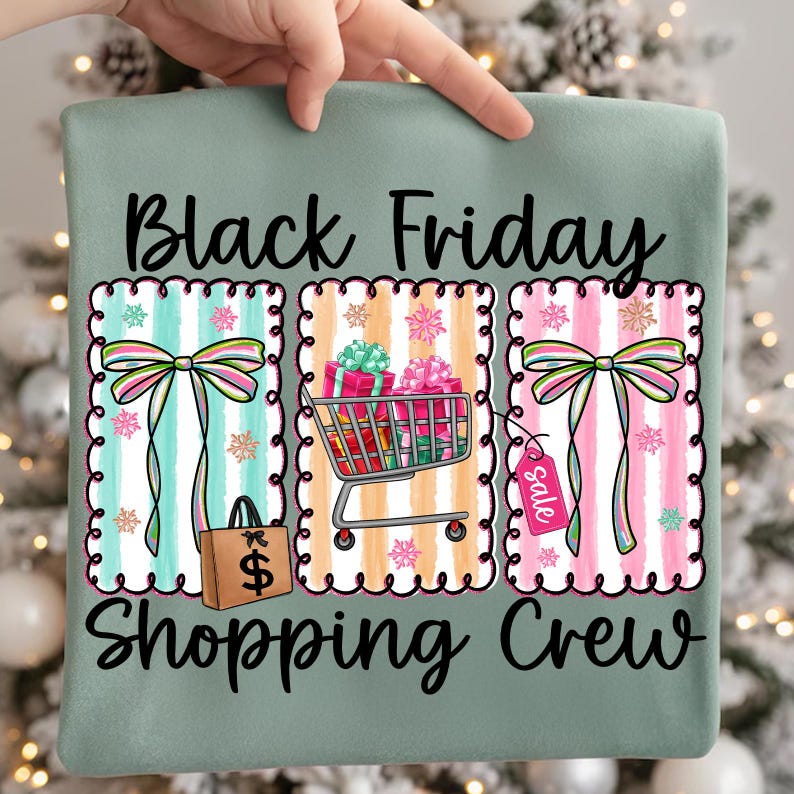 May include: A sage green graphic tee with the words "Black Friday Shopping Crew" in black script. The design features three framed sections with bows, a shopping cart with gifts, and a shopping bag.