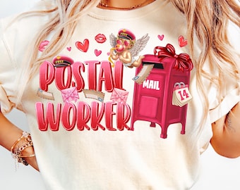 May include: A white t-shirt with a red and pink graphic design featuring a cartoon cupid holding a heart-shaped arrow, a red mailbox with the word "MAIL" on it, and the text "POSTAL WORKER".