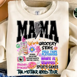 May include: A white sweatshirt with a black graphic print that says "Mama" with a lightning bolt and a checkered pattern. The graphic also includes the text "Work Grocery Store, Field Trips, Playground, School Vacation Appointments, Doctor Visits, Kitchen Practice, Make it Happen, Sports Games, The Mother Hood Tour".