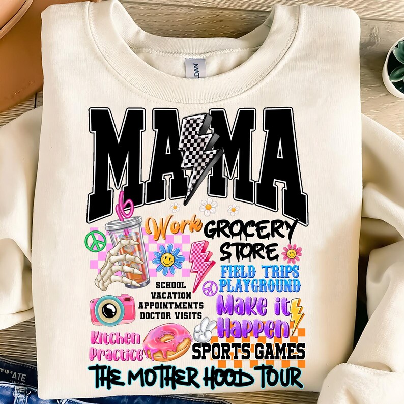May include: A white sweatshirt with a black graphic print that says "Mama" with a lightning bolt and a checkered pattern. The graphic also includes the text "Work Grocery Store, Field Trips, Playground, School Vacation Appointments, Doctor Visits, Kitchen Practice, Make it Happen, Sports Games, The Mother Hood Tour".