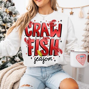 May include: White sweatshirt with red text that says "Crawfish season" with red crawfish illustrations.