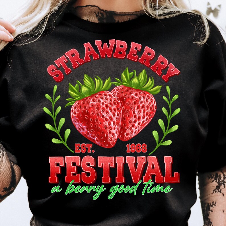 May include: Black t-shirt with a red and green graphic design featuring strawberries and the text "Strawberry Festival, a berry good time, Est. 1968".