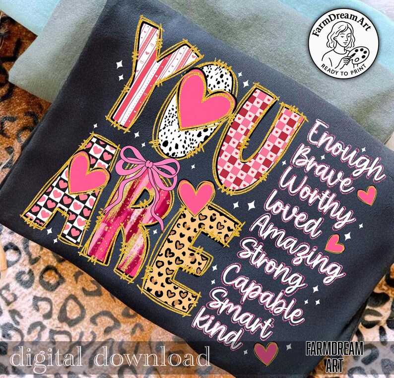May include: A dark gray t-shirt with the words "YOU ARE" in a decorative font, featuring pink hearts and patterns. The words "Enough, Brave, Worthy, Loved, Amazing, Strong, Capable, Smart, kind" are also displayed. The phrase "digital download" is at the bottom.