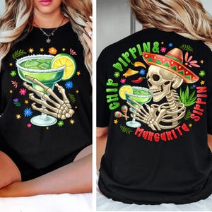 Puede incluir: Camiseta negra con un gráfico colorido de un esqueleto sosteniendo un vaso de margarita. El texto "Chip Dippin' & Sippin' Margarita" está impreso en la camiseta.
