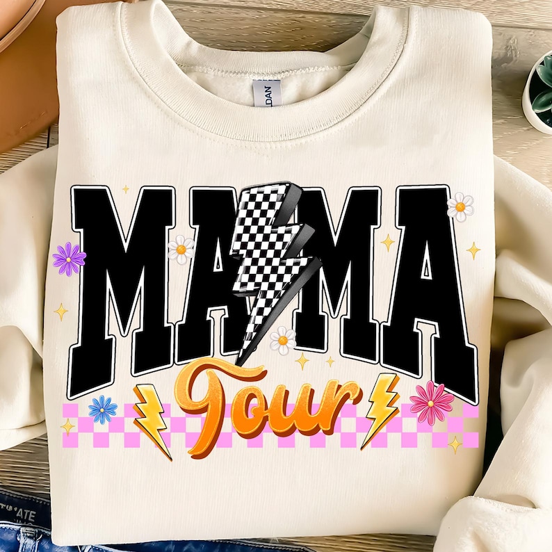 May include: A white sweatshirt with a black graphic that says "Mama Tour" with a checkered lightning bolt and pink and white checkered stripes.