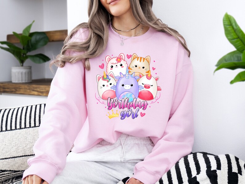 Puede incluir: Sudadera rosa con un gr&aacute;fico de adorables animales de dibujos animados, incluyendo un unicornio, un gato y un conejito. El texto "birthday girl" est&aacute; impreso en la sudadera.