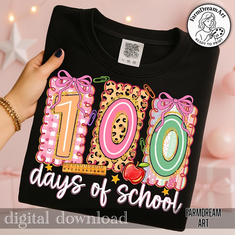 May include: Black sweatshirt featuring a colourful graphic celebrating 100 days of school. The design includes the numbers "100" in pink, orange, and green, with a ruler, apple, and the text "days of school".