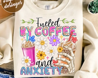 Puede incluir: Un diseño de sublimación con un fondo blanco y el texto "Fueled by Coffee and Anxiety" en letras rosas, azules y marrones. El texto está rodeado de flores coloridas y dos bebidas de café, una con una taza rosa y la otra con una mano de esqueleto sosteniendo una taza marrón.