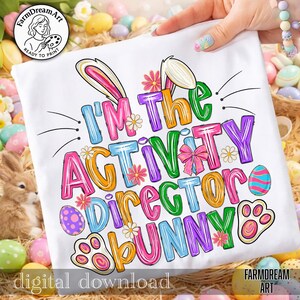 May include: White t-shirt with the text "I'M the ACTIVITY DIRECTOR BUNNY" in colorful, playful letters. The design includes bunny ears, flowers, and Easter egg details, perfect for Easter celebrations. The words "digital download" are also visible.