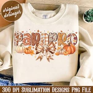 May include: A beige sweatshirt with a design of the word "papparo" in brown, orange, and white patterned letters with a brown and gold bow and pumpkins.
