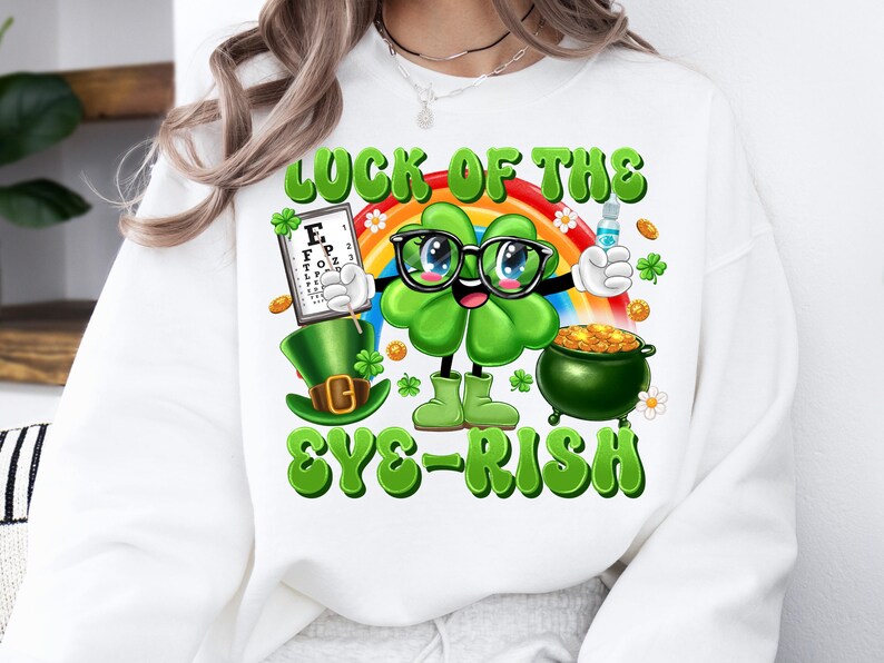 May include: White sweatshirt with a green shamrock cartoon character wearing glasses and holding a pot of gold. The text "Luck of the Eye-rish" is printed on the shirt.