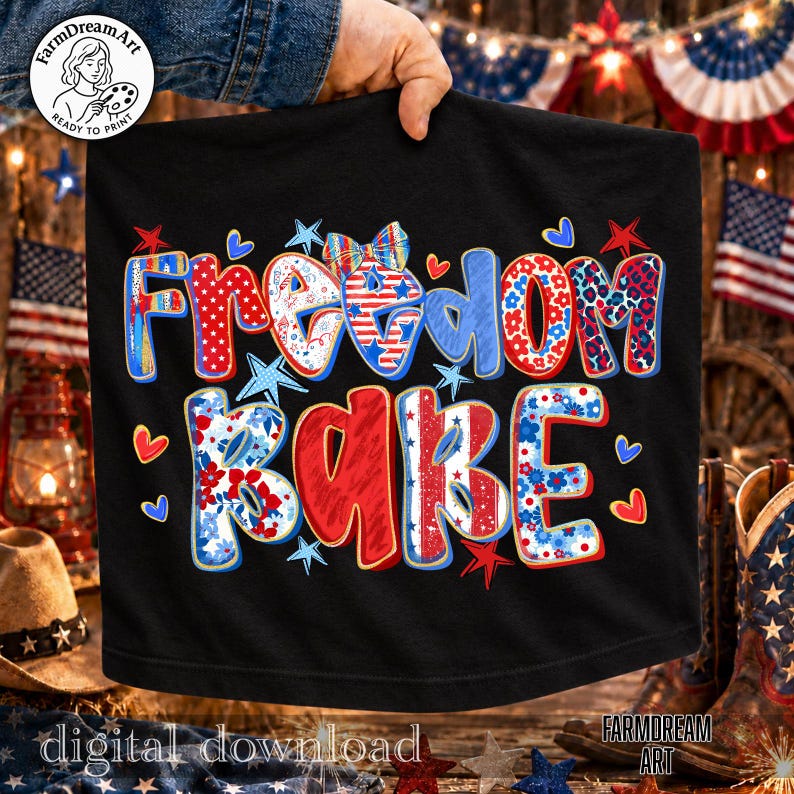 May include: Black t-shirt with the words "Freedom Babe" in red, white, and blue lettering. The design includes stars, hearts, and floral patterns, evoking a patriotic theme. The words "digital download" and "Farmdream Art" are also visible.