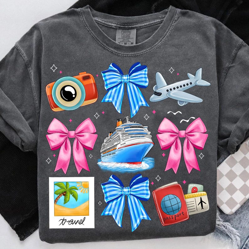 Puede incluir: Una camiseta gris con tem&aacute;tica de viaje. La camiseta presenta un crucero, una c&aacute;mara, un pasaporte, un avi&oacute;n y varios lazos en azul y rosa.