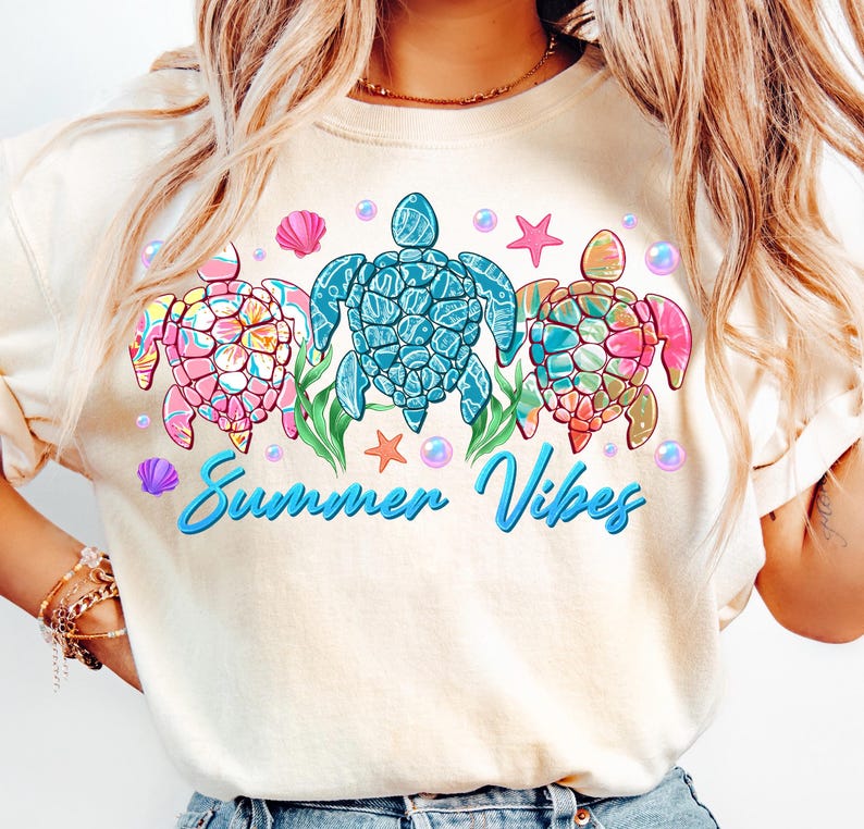 May include: A white t-shirt with a graphic of three colorful sea turtles with the text "Summer Vibes" in blue.